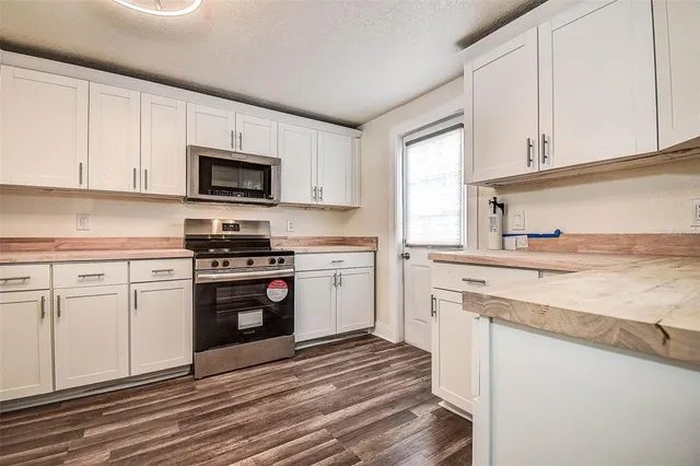 a kitchen with granite countertop white cabinets and stainless steel appliances