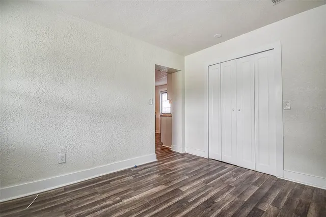 a view of an empty room with wooden floor and closet