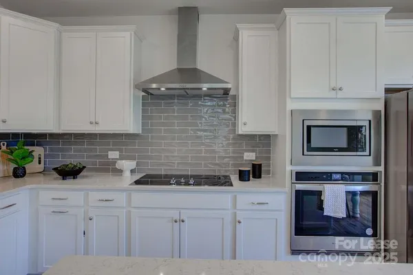 a kitchen with stainless steel appliances white cabinets and a stove top oven