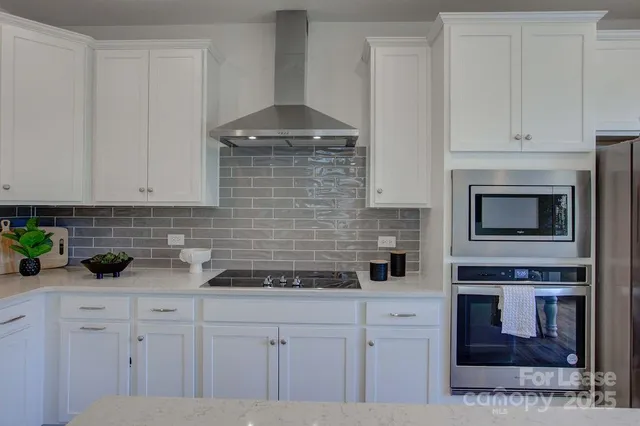 a kitchen with stainless steel appliances white cabinets and a stove top oven