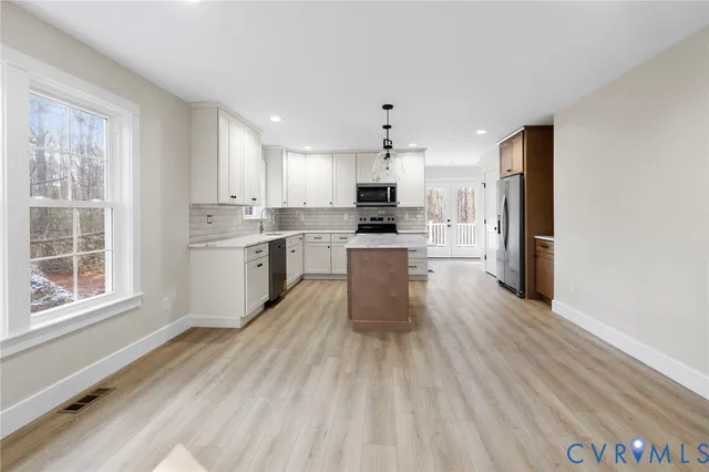 a large kitchen with cabinets wooden floor and stainless steel appliances