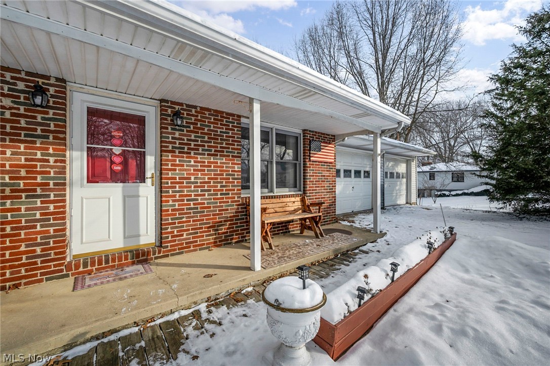 3830 Jerusalem Road Vermilion, OH 44089 - Photo 5 of 49 Snow covered property entrance with brick siding, covered porch, and an attached garage