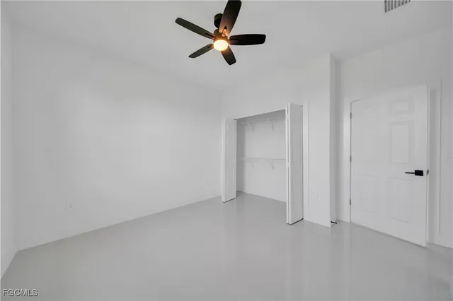an empty room with ceiling fan and windows