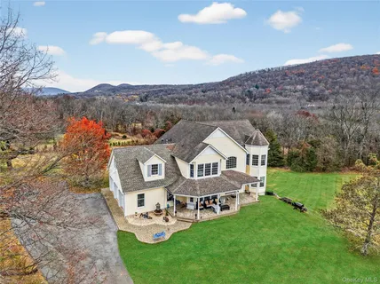 a view of a house with a big yard and large trees