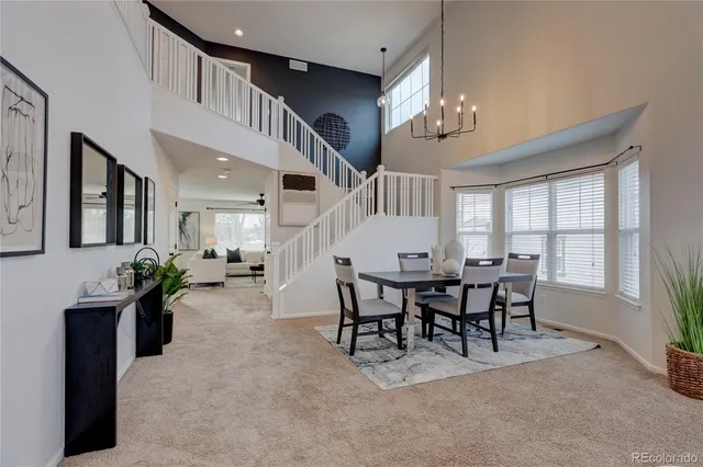a dining room with wooden floor a chandelier a wooden table and chairs