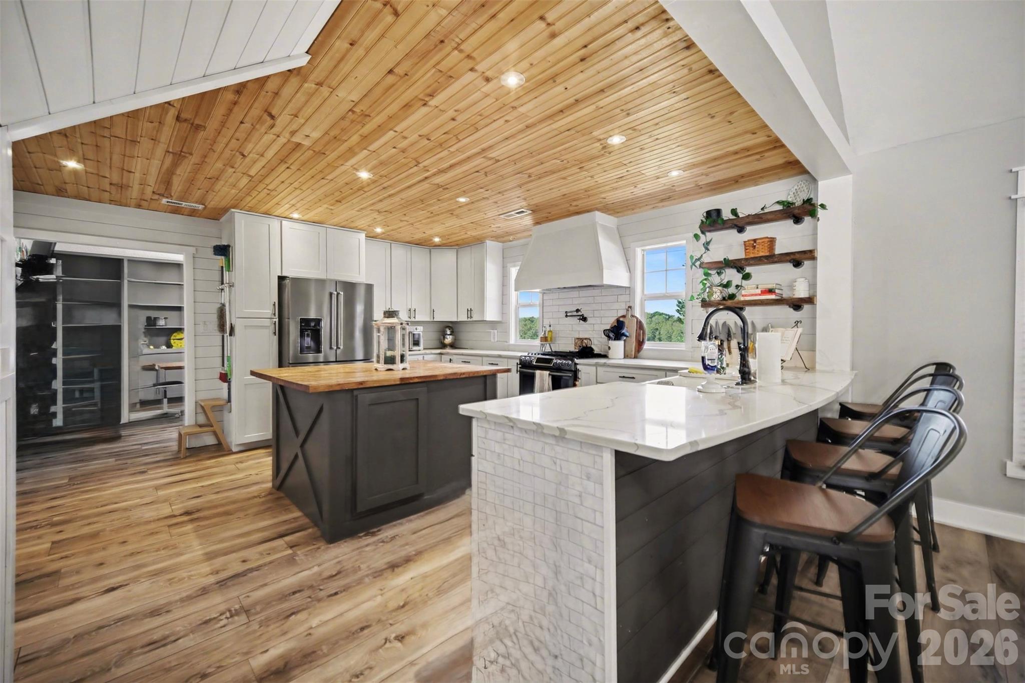 5226 Old Plank Road Iron Station, NC 28080 - Photo 10 of 45 a kitchen with stainless steel appliances kitchen island granite countertop a table chairs in it and wooden floors