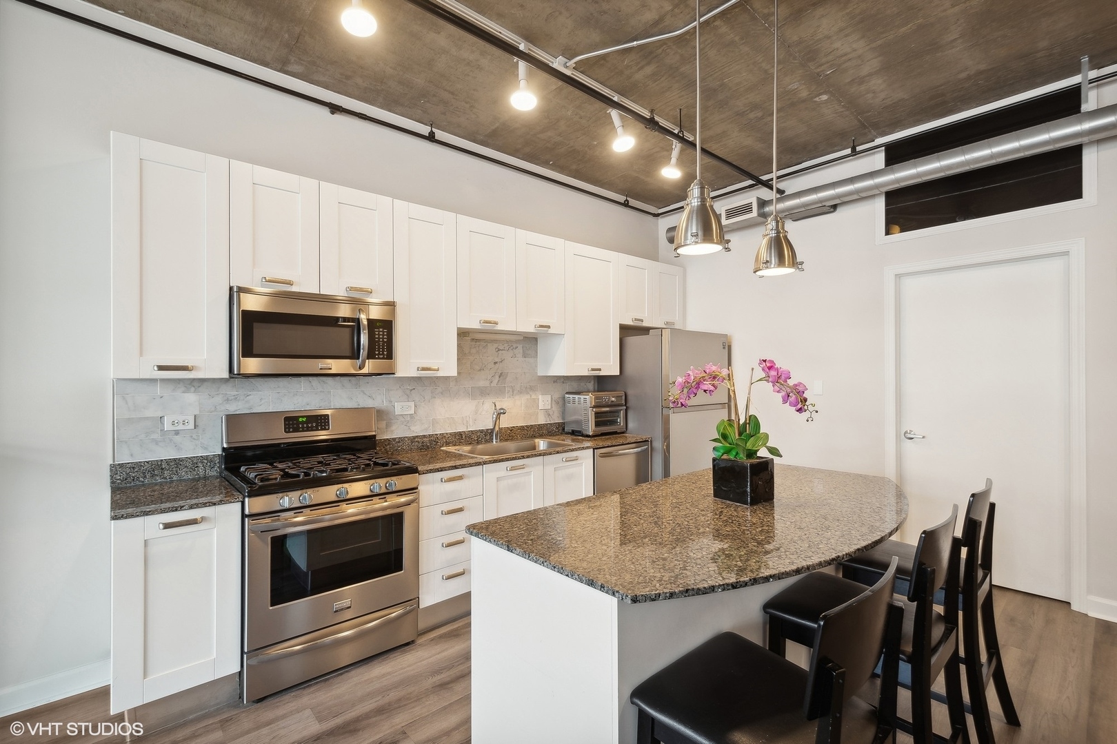 111 South Morgan Street, Unit 607 Chicago, IL 60607 - Photo 3 of 12 a kitchen with granite countertop stainless steel appliances a table chairs stove and microwave