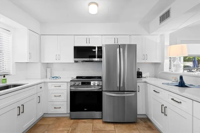 a kitchen with white cabinets and stainless steel appliances