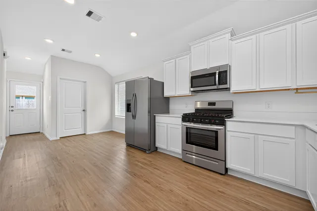 a kitchen with stainless steel appliances white cabinets and a stove top oven