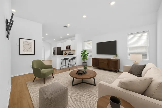 a living room with furniture a flat screen tv and kitchen view