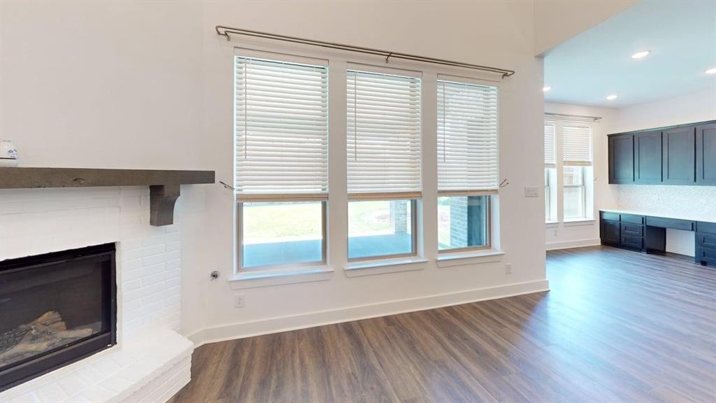 9628 Boulder Pt Road Oak Point, TX 75068 - Photo 6 of 35 White brick fireplace with a wood-finish mantel, multiple windows with blinds, wood-finish flooring, and recessed lighting
