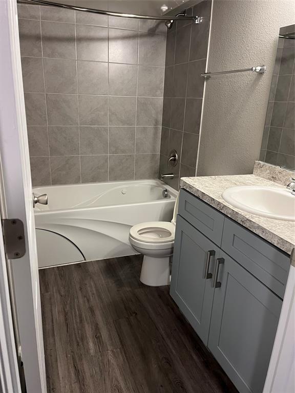 6108 Abrams Road, Unit 528 Dallas, TX 75231 - Photo 4 of 7 Full bathroom with a textured wall, vanity, bathtub / shower combination, and dark wood-style floors