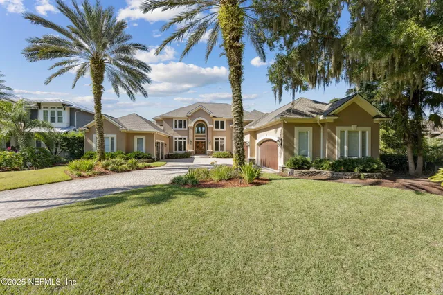 a front view of a house with a yard and palm trees