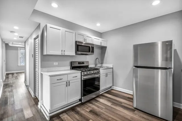 a kitchen with a refrigerator stove and wooden floor