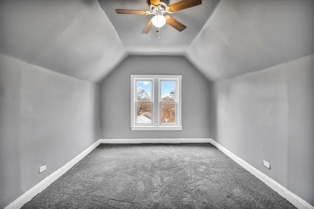 an empty room with chandelier fan and windows