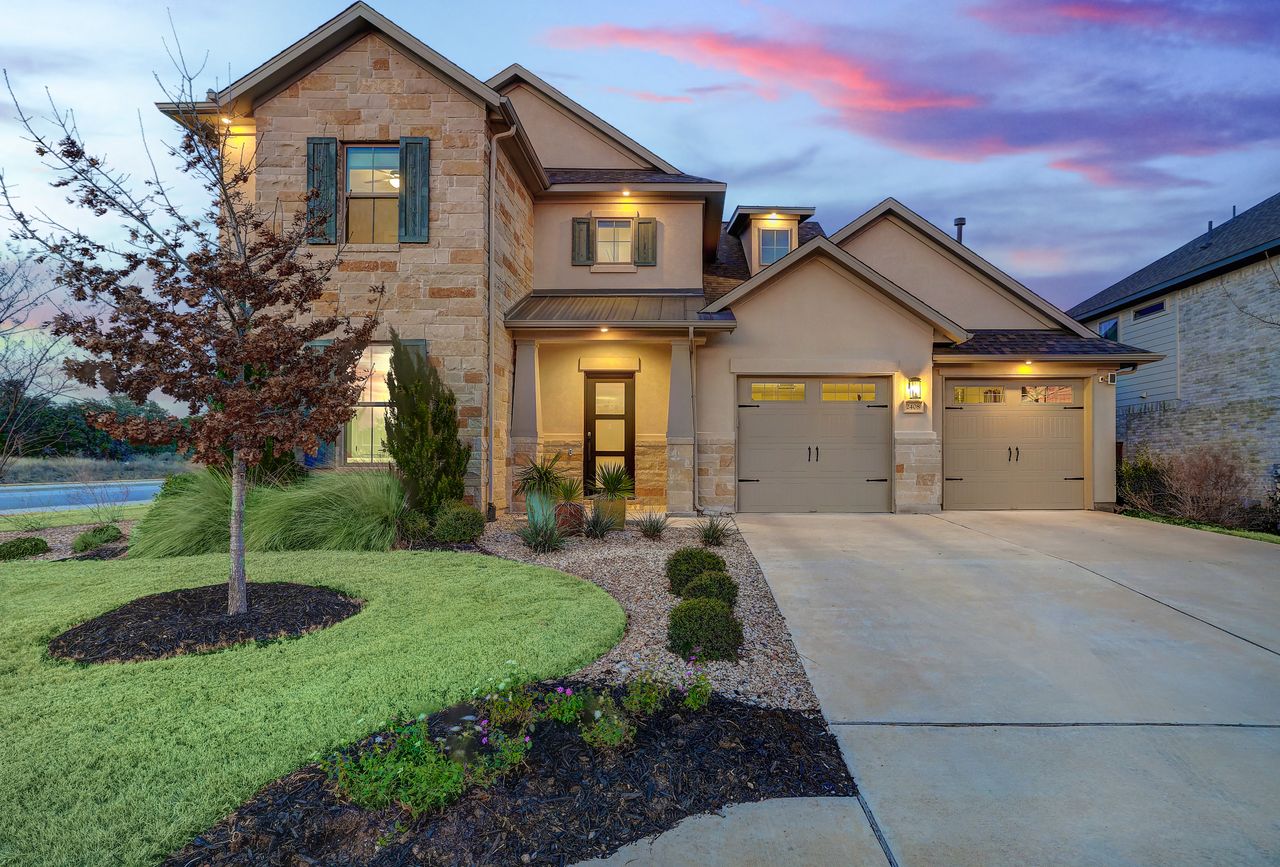 View of front of property with stone siding, stucco siding, driveway, a garage, and a front lawn