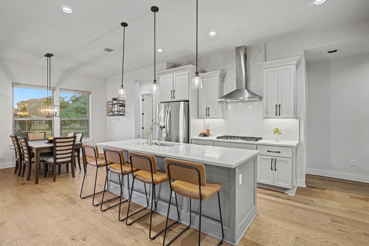 2408 Nate's Place Georgetown, TX 78633 - Photo 12 of 40 Kitchen featuring a kitchen bar, hanging light fixtures, a center island with sink, and white cabinetry