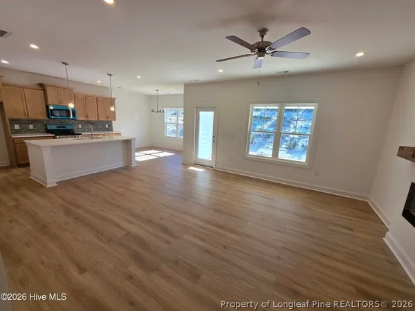 a view of an empty room with window and wooden floor