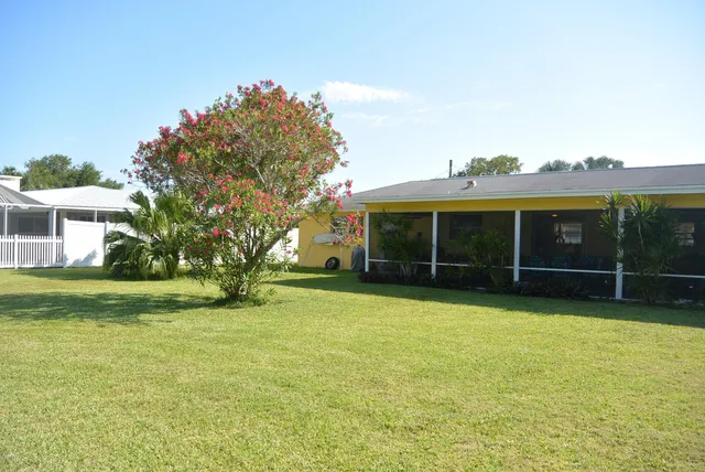 a view of a house with a yard and a large tree