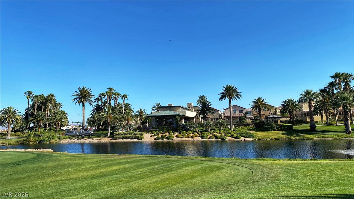 489 Foster Springs Road Las Vegas, NV 89148 - Photo 18 of 30 A tranquil golf course green borders a shimmering lake, framed by palm trees and distant homes.