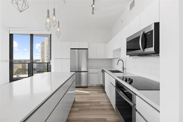 a kitchen with stainless steel appliances white cabinets and a stove top oven
