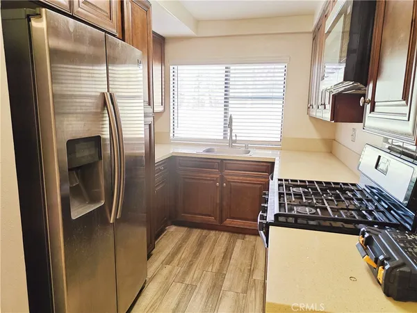 a view of an empty room with kitchen and wooden floor