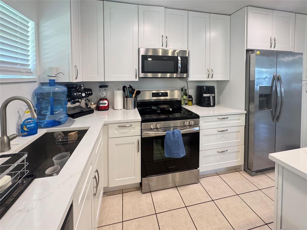 151 Southwest 15th Street Pompano Beach, FL 33060 - Photo 12 of 36 a kitchen with a stove a sink and a refrigerator with wooden cabinets