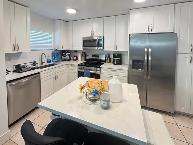 a kitchen with stainless steel appliances granite countertop a sink a stove a refrigerator a washer and dryer