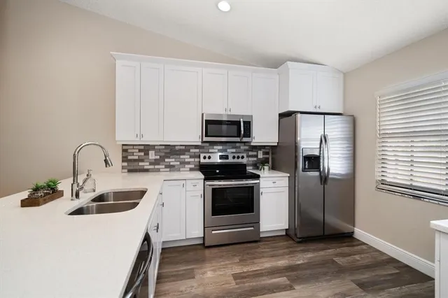 a kitchen with stainless steel appliances a refrigerator stove and white cabinets