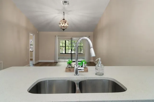 a kitchen with a sink a chandelier and living room view