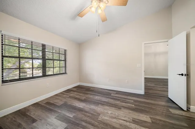a view of empty room with wooden floor and fan