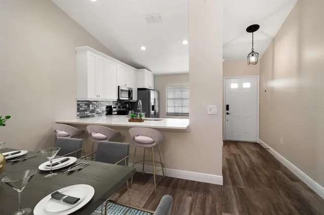 a kitchen with stainless steel appliances a dining table chairs and a refrigerator