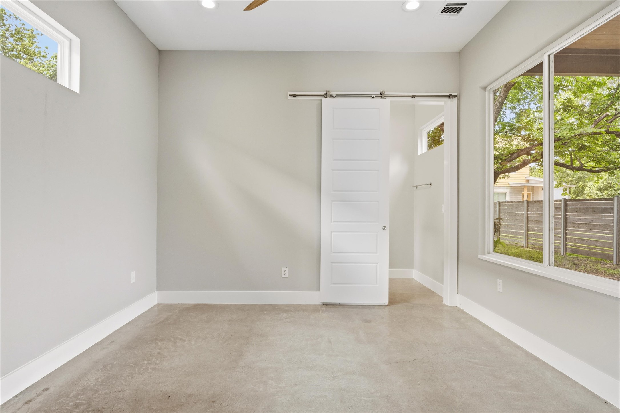 1210 Stobaugh Street, Unit B Austin, TX 78757 - Photo 24 of 40 A spacious room features a modern barn door and ample natural light through large windows.
