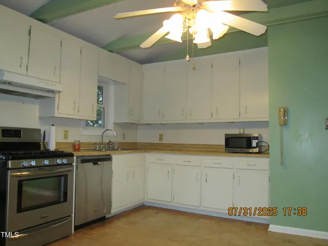 a kitchen with granite countertop a stove a sink and dishwasher with white cabinets