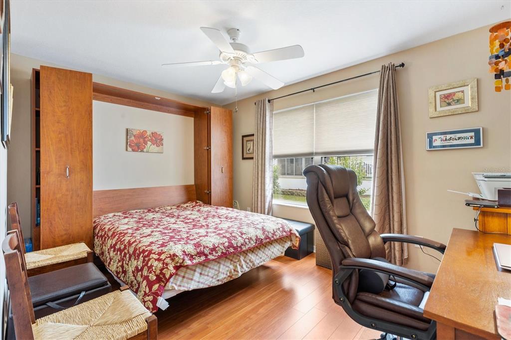 470 Oboe Way The Villages, FL 32162 - Photo 21 of 42 a bedroom with a bed a desk and chair with wooden floor