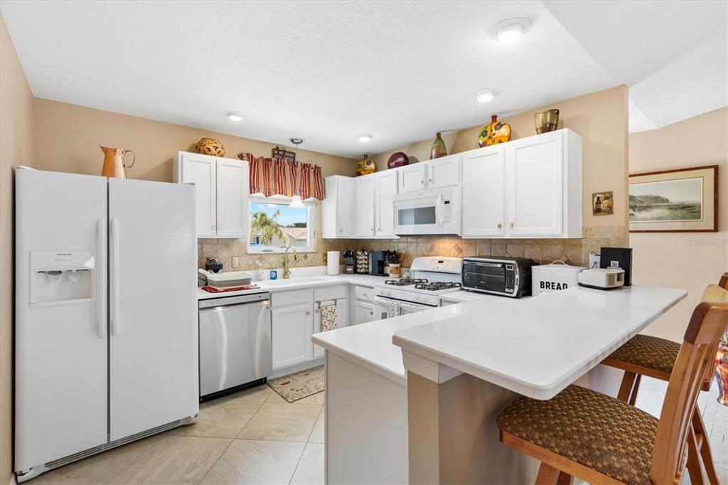 470 Oboe Way The Villages, FL 32162 - Photo 4 of 42 a kitchen with a refrigerator a stove a sink dishwasher and white cabinets with wooden floor