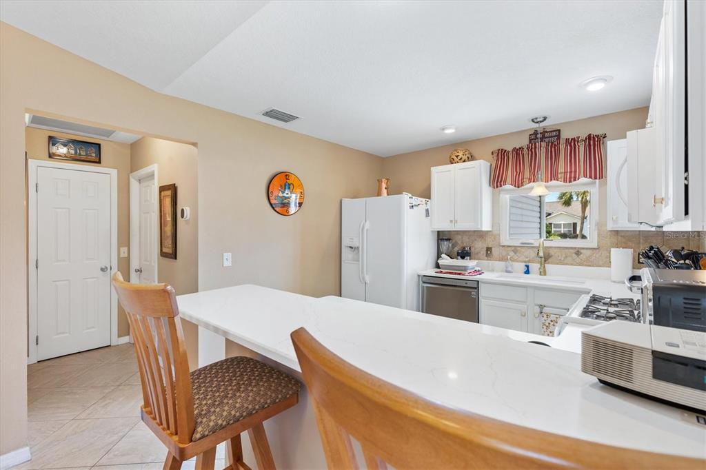 470 Oboe Way The Villages, FL 32162 - Photo 6 of 42 a kitchen with stainless steel appliances granite countertop a white refrigerator a stove a sink dishwasher and white cabinets with wooden floor