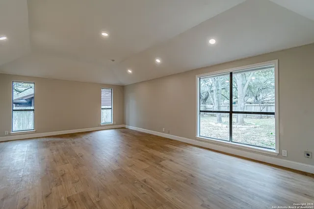 a view of an empty room with wooden floor and windows