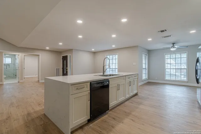 a large kitchen with granite countertop a large counter top and stainless steel appliances