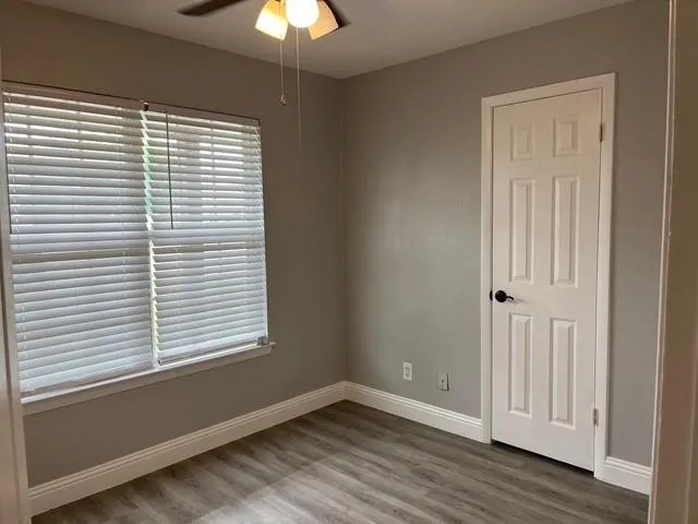 a view of an empty room with a window and wooden floor