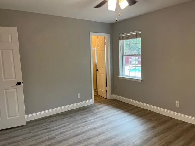 an empty room with wooden floor closet and windows