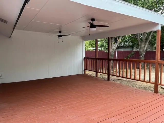 an empty room with wooden floor fan and a ceiling fan