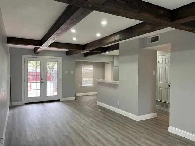 a view of an empty room with wooden floor and a window