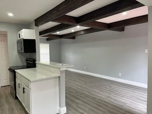 a kitchen that has a sink and a stove with wooden floor