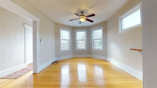 a view of an empty room with window and chandelier fan