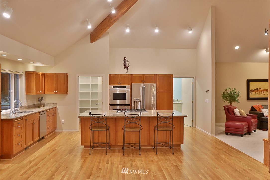 5657 Cameron Road Freeland, WA 98249 - Photo 14 of 40 a view of a kitchen with kitchen island granite countertop wooden floors and stainless steel appliances