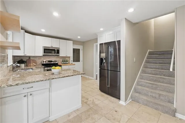 a kitchen with stainless steel appliances granite countertop a refrigerator a stove a sink and a microwave