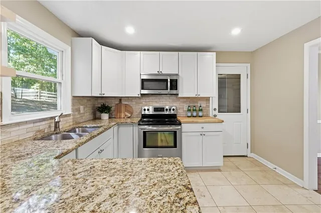 a kitchen with granite countertop a stove sink and microwave