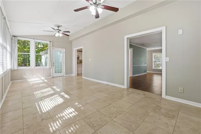a view of an empty room with window and chandelier fan