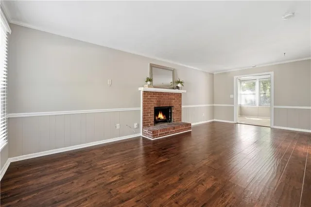 an empty room with wooden floor fireplace and windows